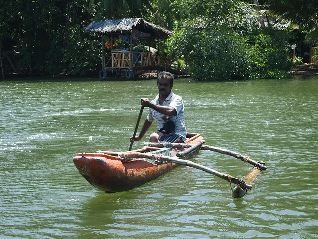 A local paddler in an outrigger canoe on Madu Ganga; destination life, not a safari vessel.